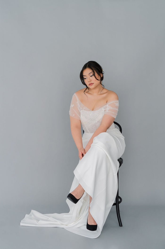 Romantic off the shoulder wedding dress by Catherine Langlois. Fit and flare silhouette accentuates the body in a modern intrepretation of delicate design. Inclusive size wedding dresses made in Canada.